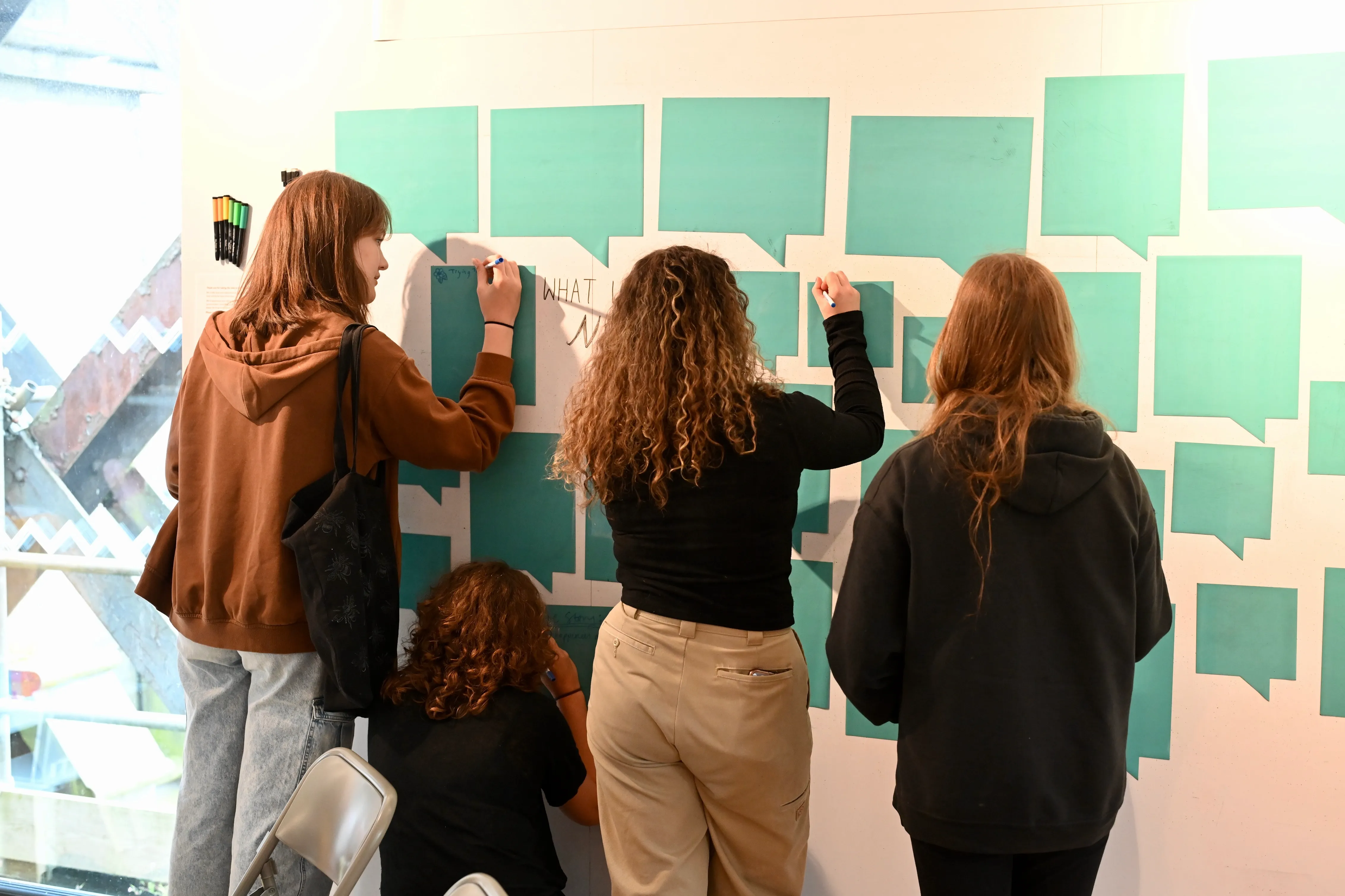 Young people brainstorming ideas on a wall.