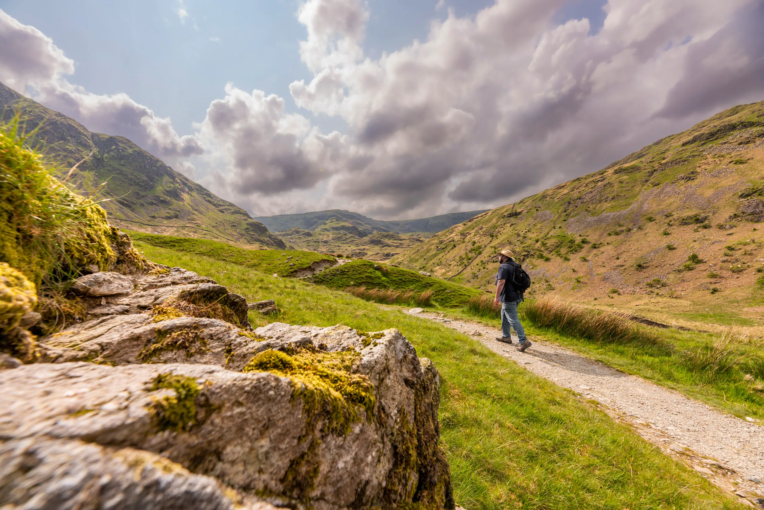 A visitor walking on Haweswater nature trail, a gravel path with an expansive view across the lake and valley