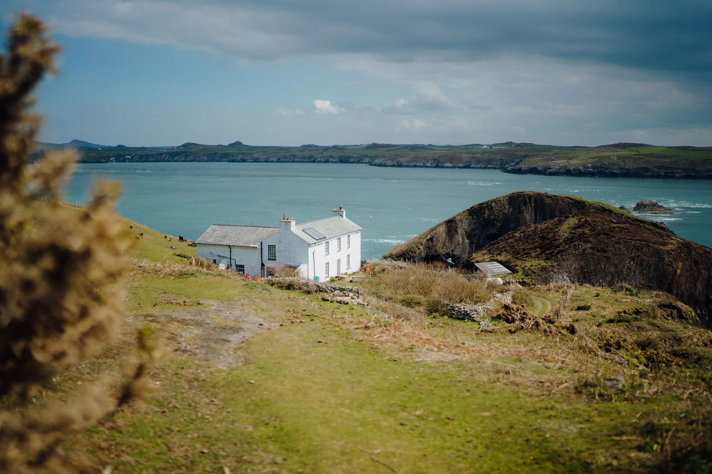 A painted white, stone building, on the edge of Ramsay island with a view looking out to sea.