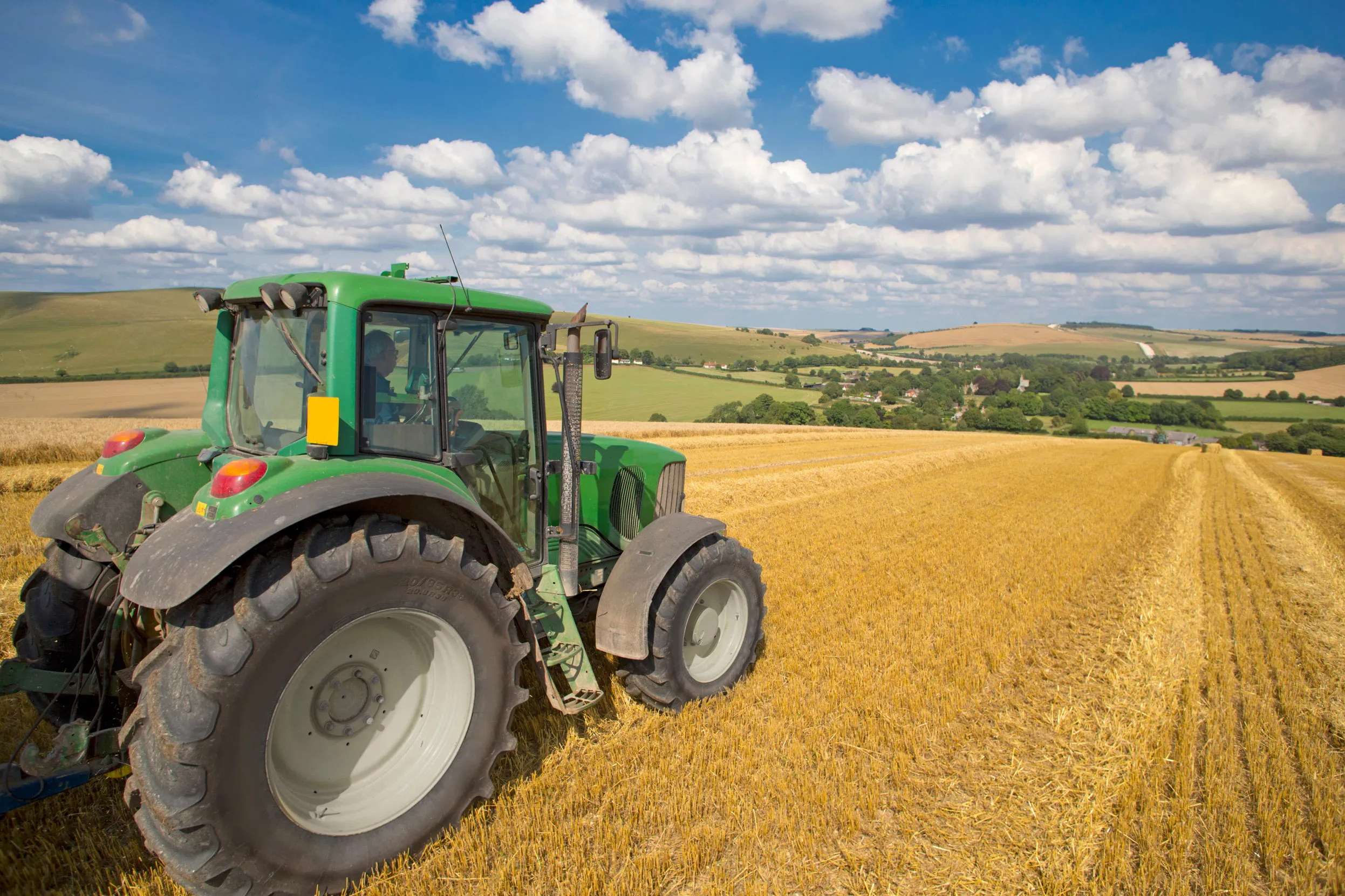 A tractor harvesting a field of golden crops.