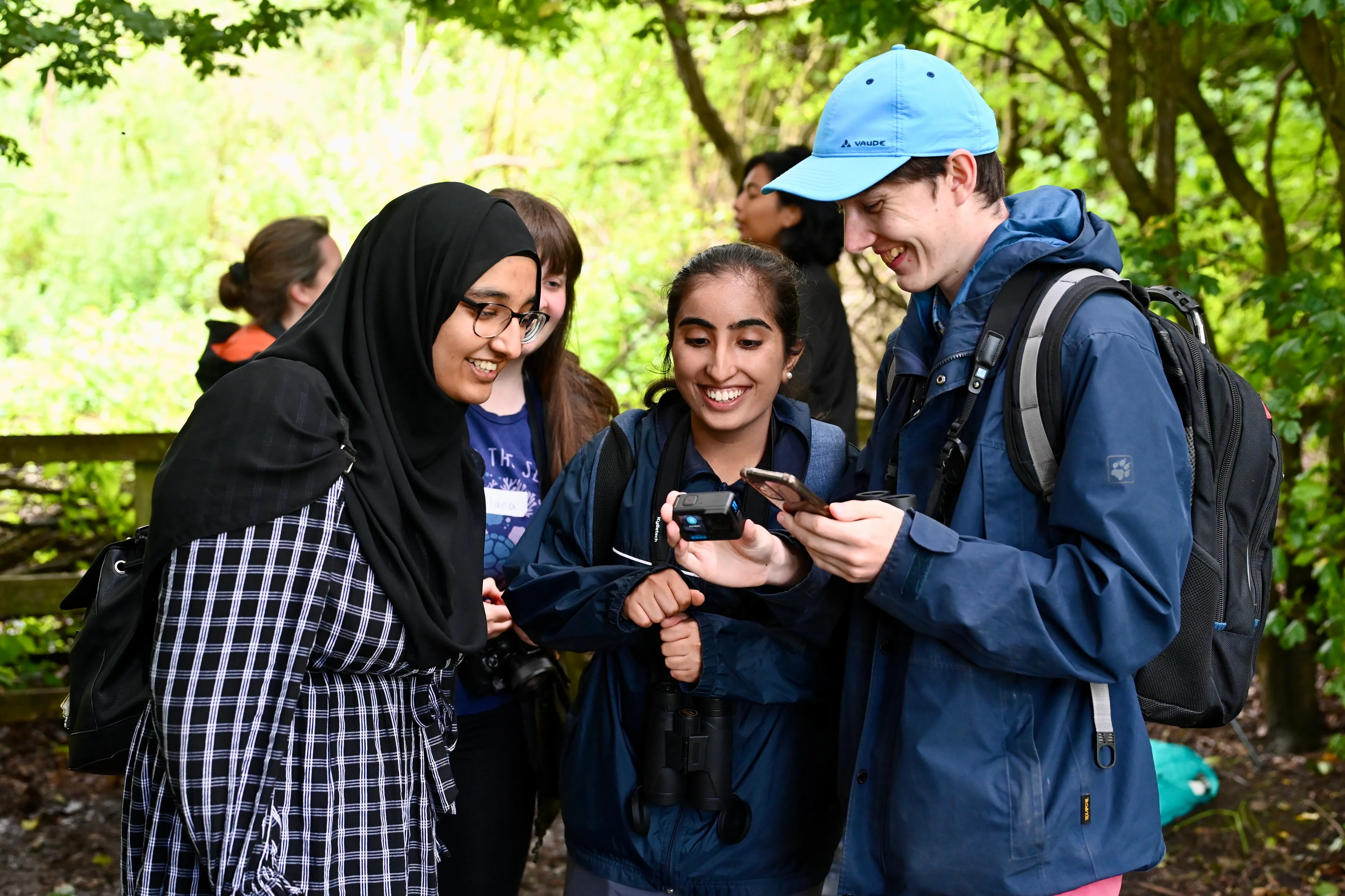 Young people checking their camera, working together in the woods.