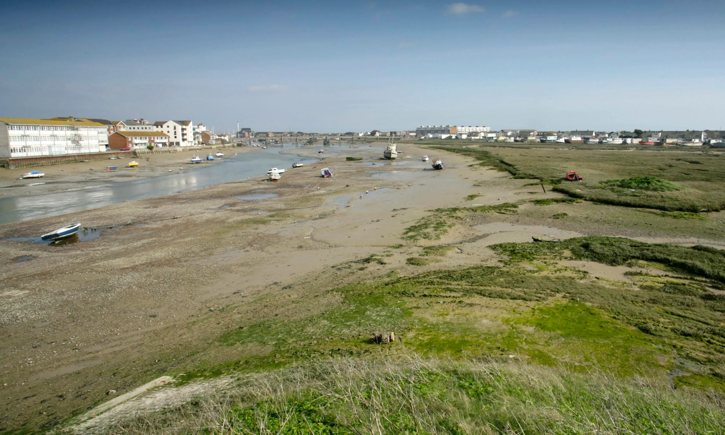 A shot of Adur Estuary, looking over grassland towards boats in the Estuary.