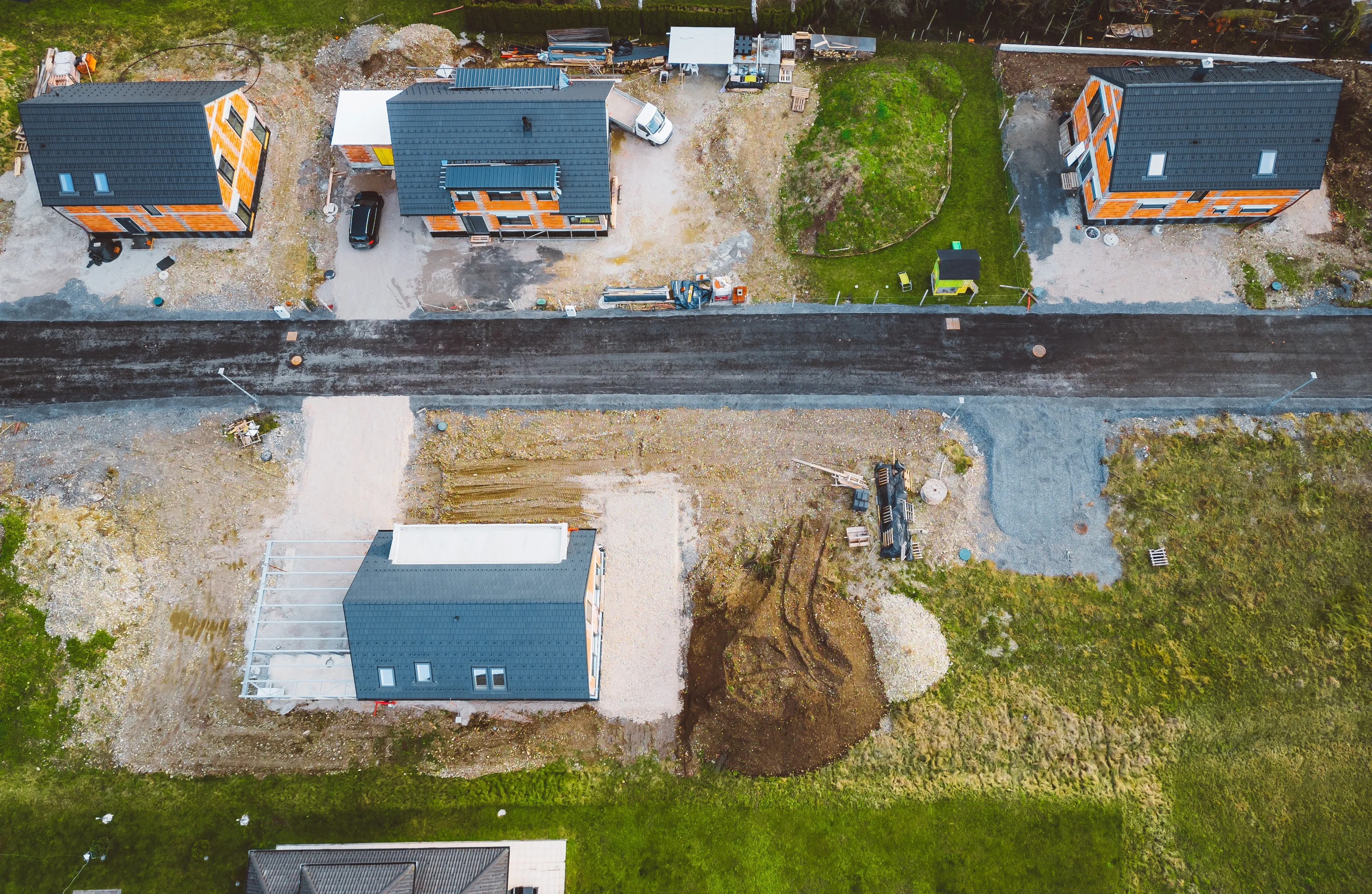 Aerial view of four houses under construction, surrounded by machinery and construction materials.