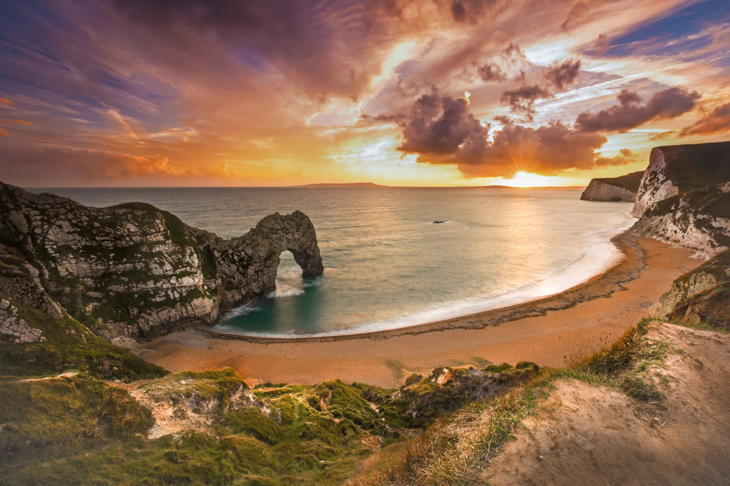 Durdle door, seen from the cliffs above, looking across the beach and out to sea.