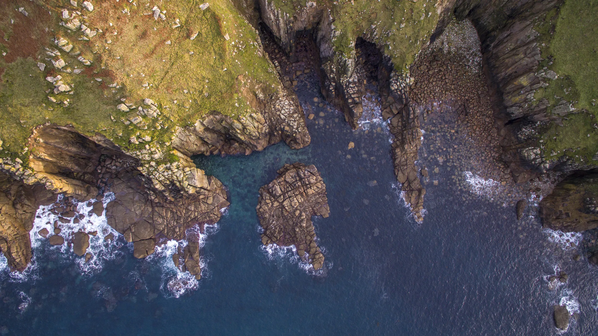 Birds eye view of where costal cliffs meet the sea.