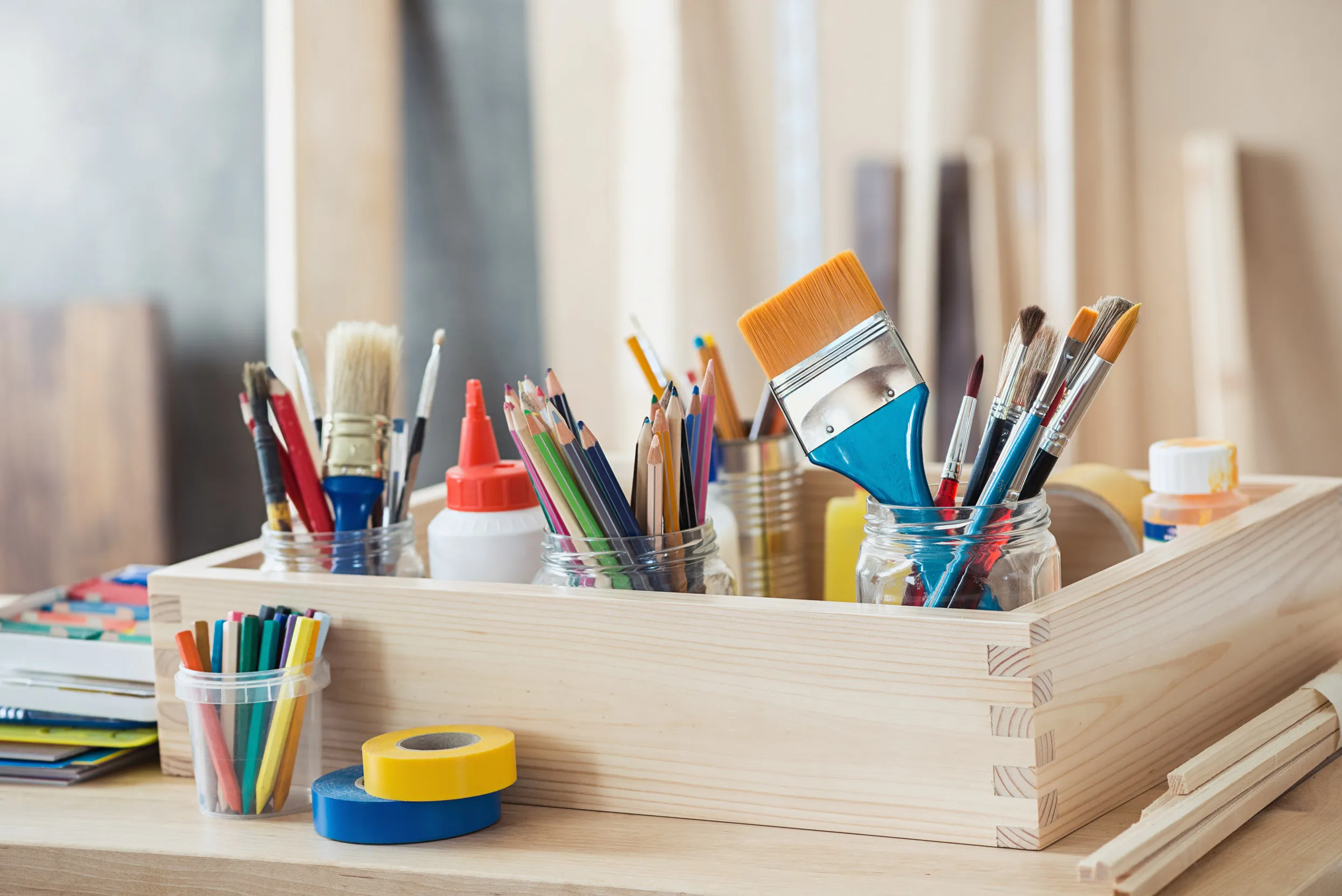 A wooden box sat on a table with a neat array of paintbrushes and craft supplies.