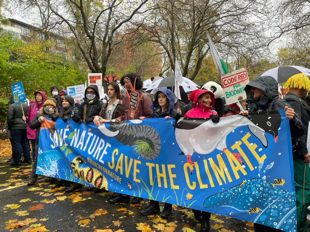 Protestors group together to hold a giant banner that says "Save nature, save the climate".