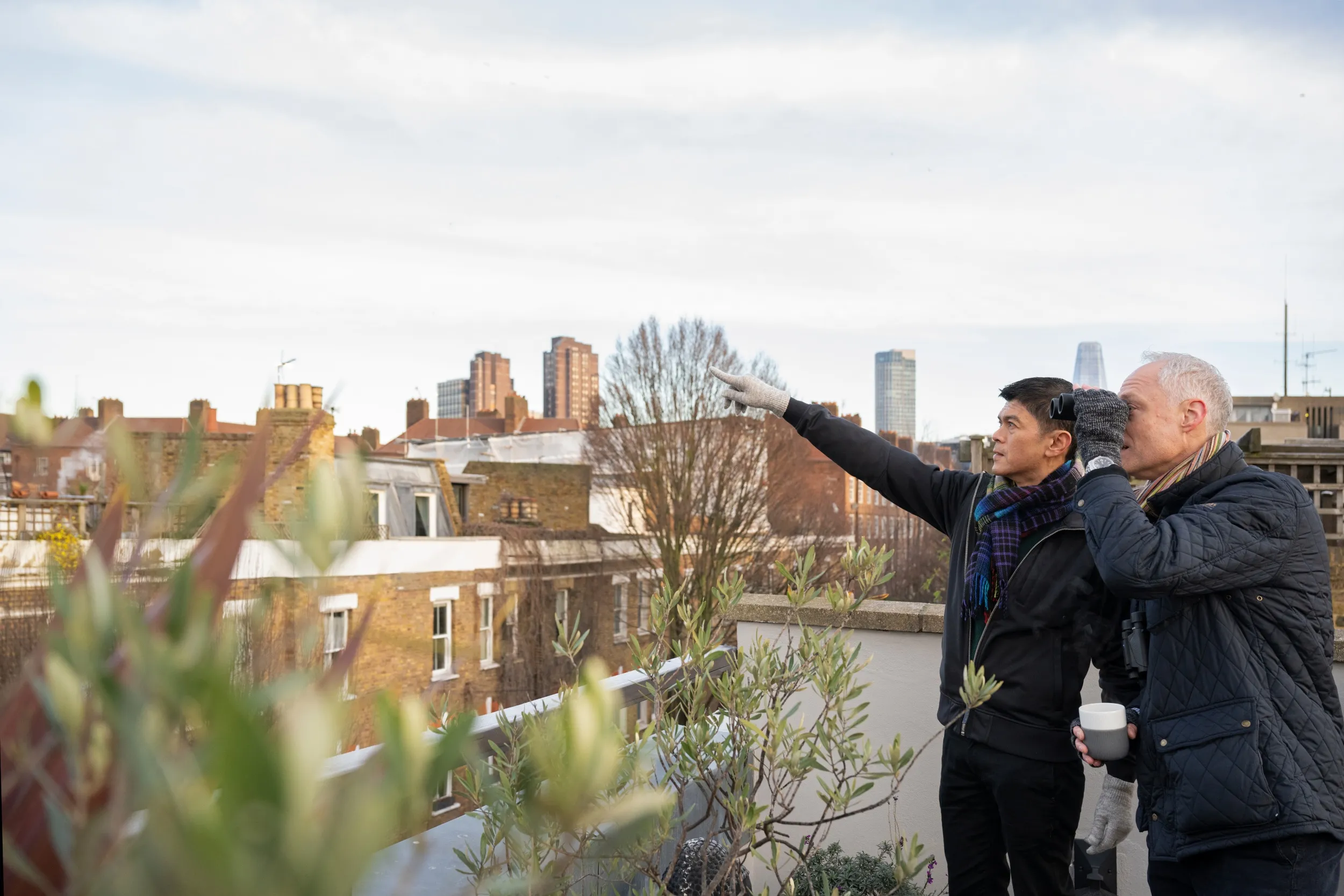 Two people birdwatching from an urban rooftop.