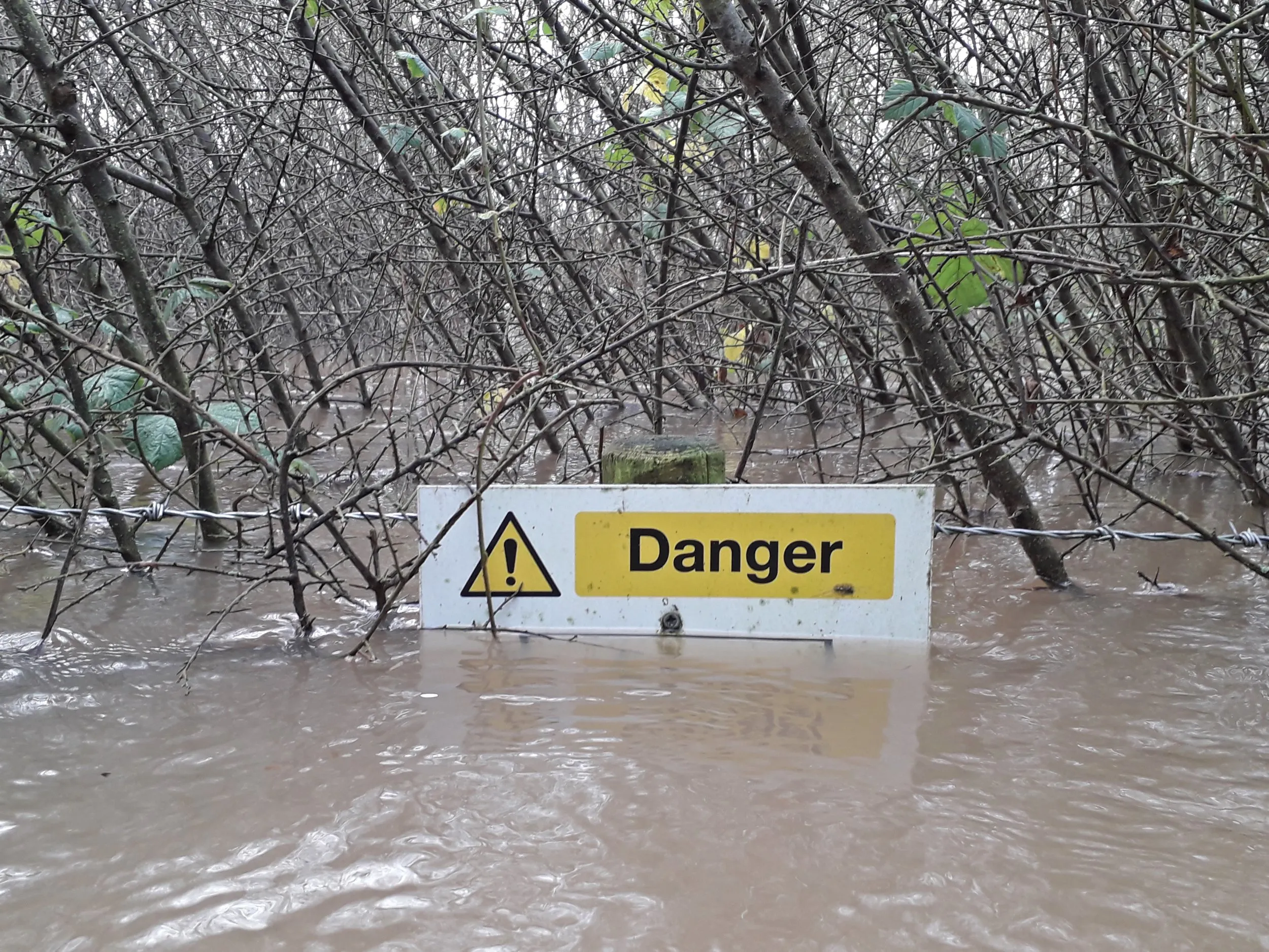 RSPB Langford Lowfields, with flood water almost submerging a sign that reads 'Danger'.